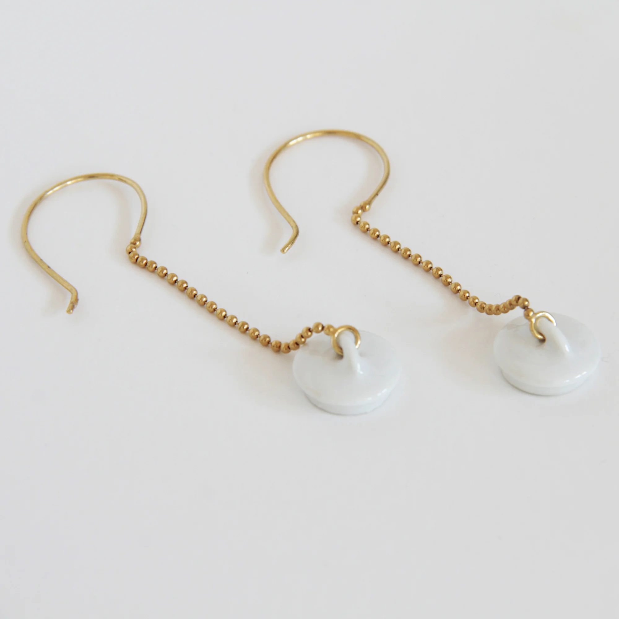Pendientes dorados y porcelana Tapón